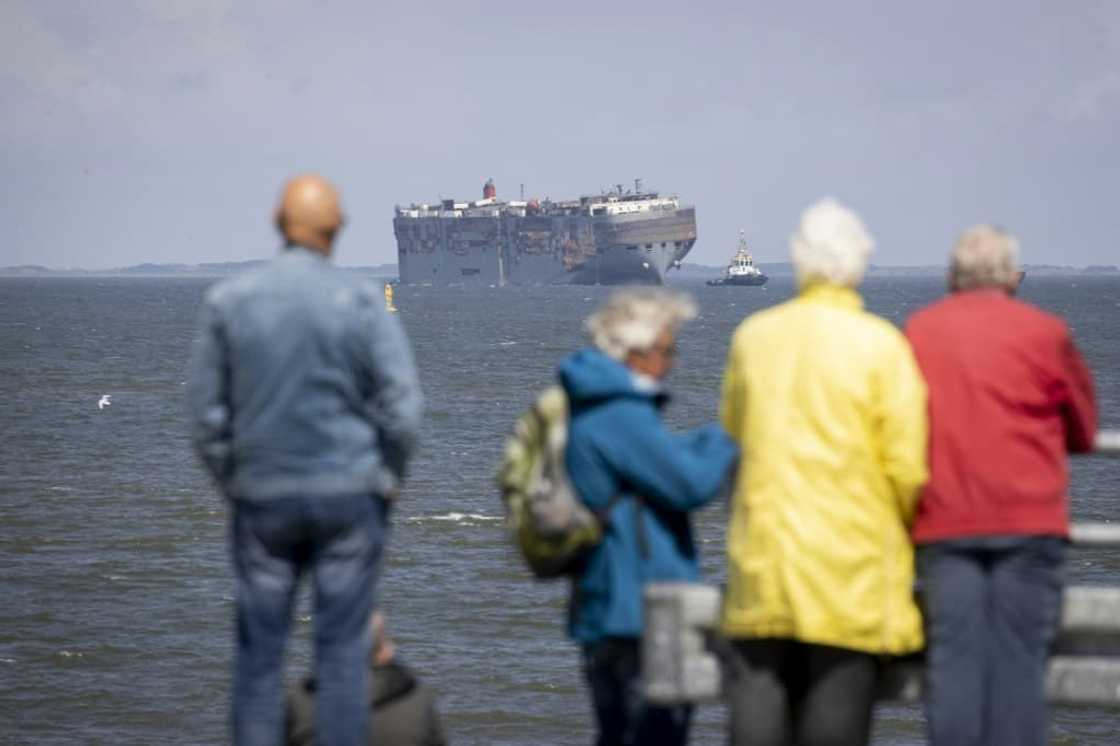 Dozens of people turned out to watch the ship being towed into port