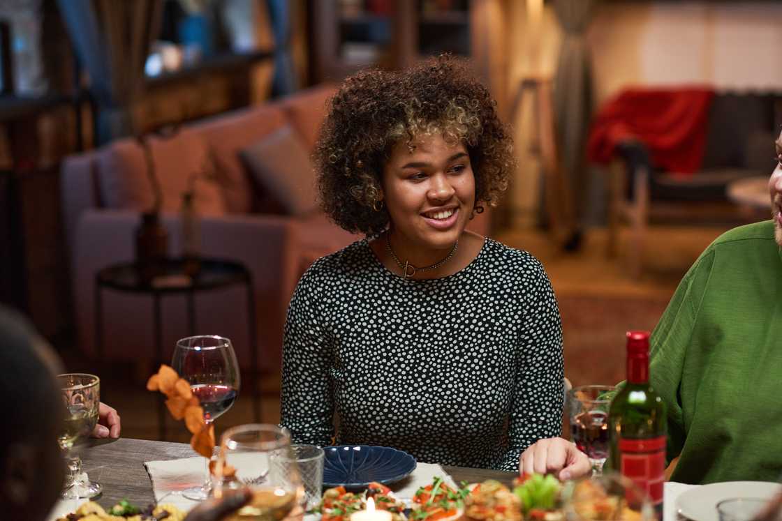 Friends laughing around a restaurant dinner table while one woman sits quietly. Friends laughing around a restaurant dinner table while one woman sits quietly.