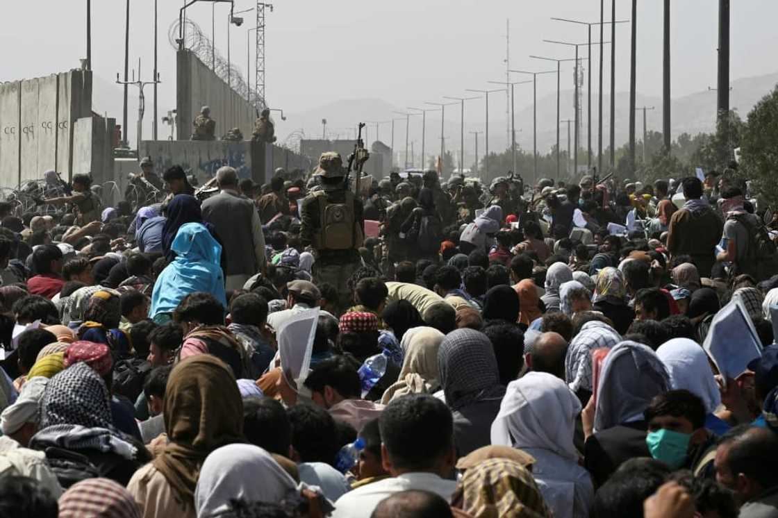 Afghans gather on a roadside near the military part of the airport in Kabul on August 20, 2021, hoping to flee from the country after the Taliban's military takeover of Afghanistan Afghans gather on a roadside near the military part of the airport in Kabul on August 20, 2021, hoping to flee from the country after the Taliban's military takeover of Afghanistan