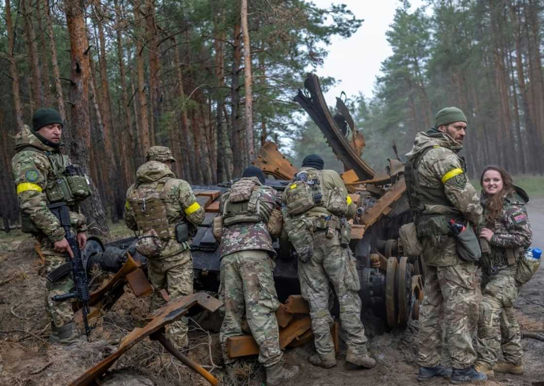 Ukrainian soldiers and volunteer fighters inspect a destroyed Russian tank in eastern Ukraine