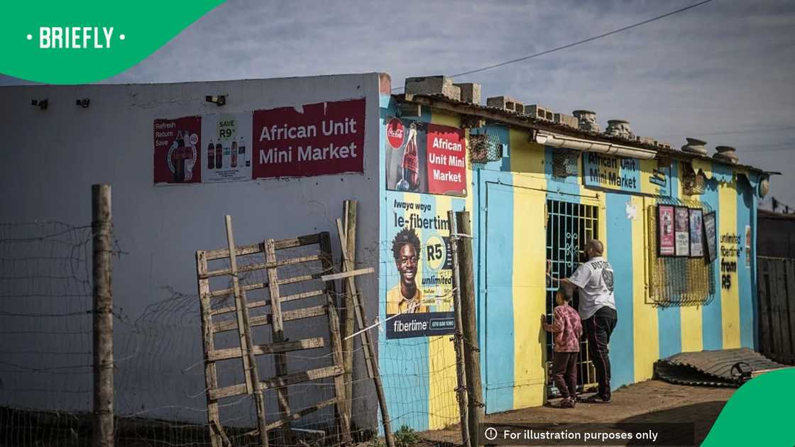 A man and a child speak through a grid to workers cleaning up the African Unit Mini Market, a spaza shop (Township convenience store) owned by a South African man of Somali origin