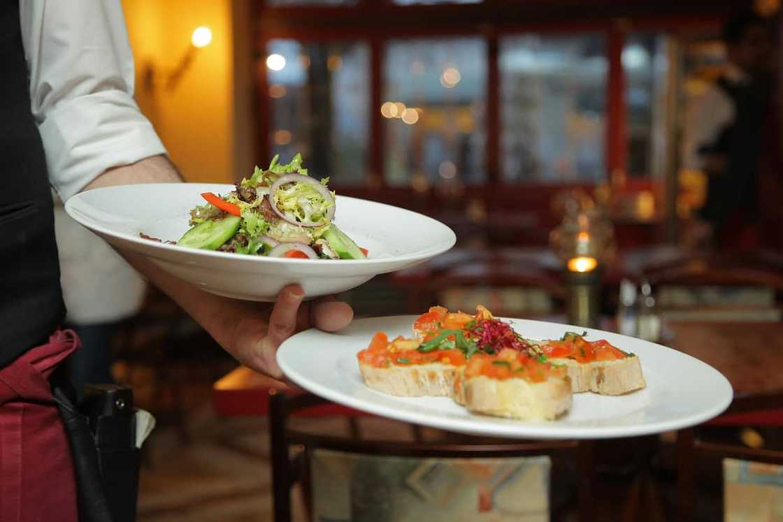 A chef holding pastry dishes on white ceramic plates