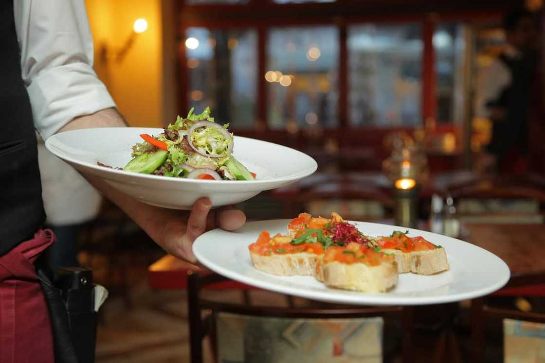 A chef holding pastry dishes on white ceramic plates A chef holding pastry dishes on white ceramic plates