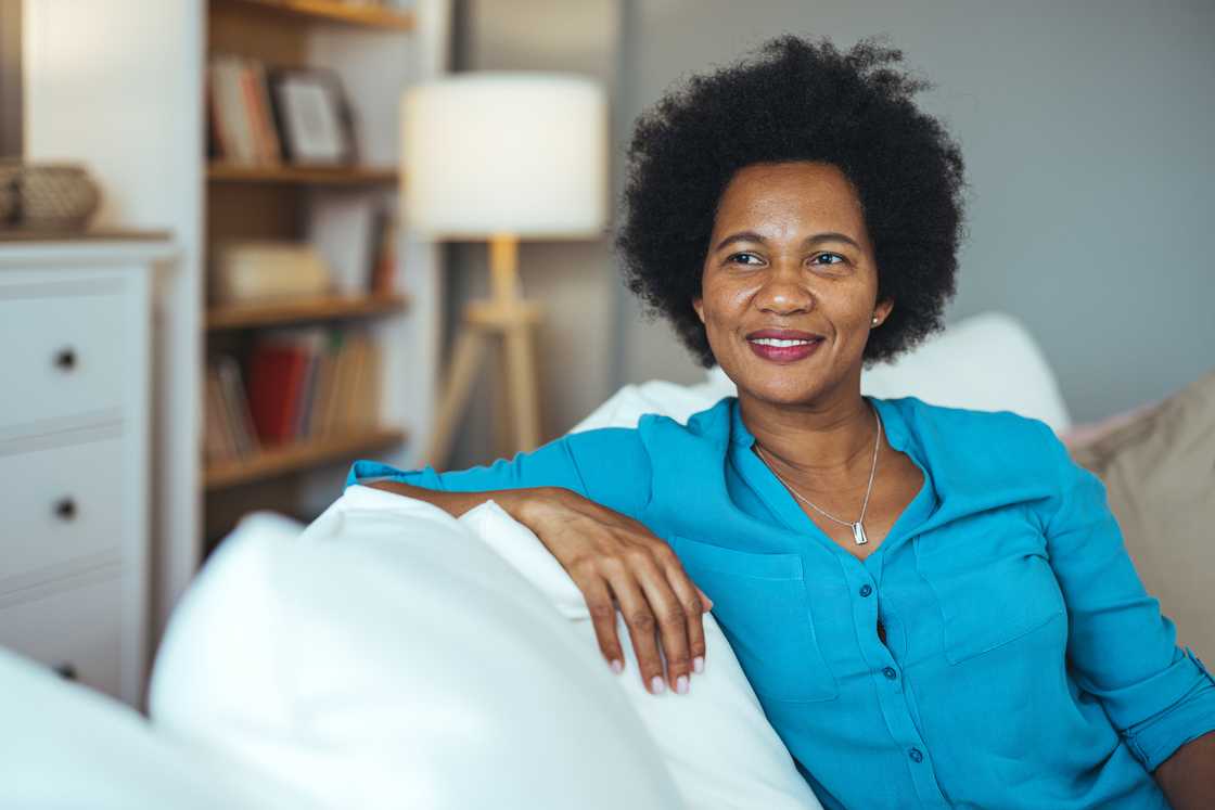 A happy mature woman smiling while sitting on a sofa at home