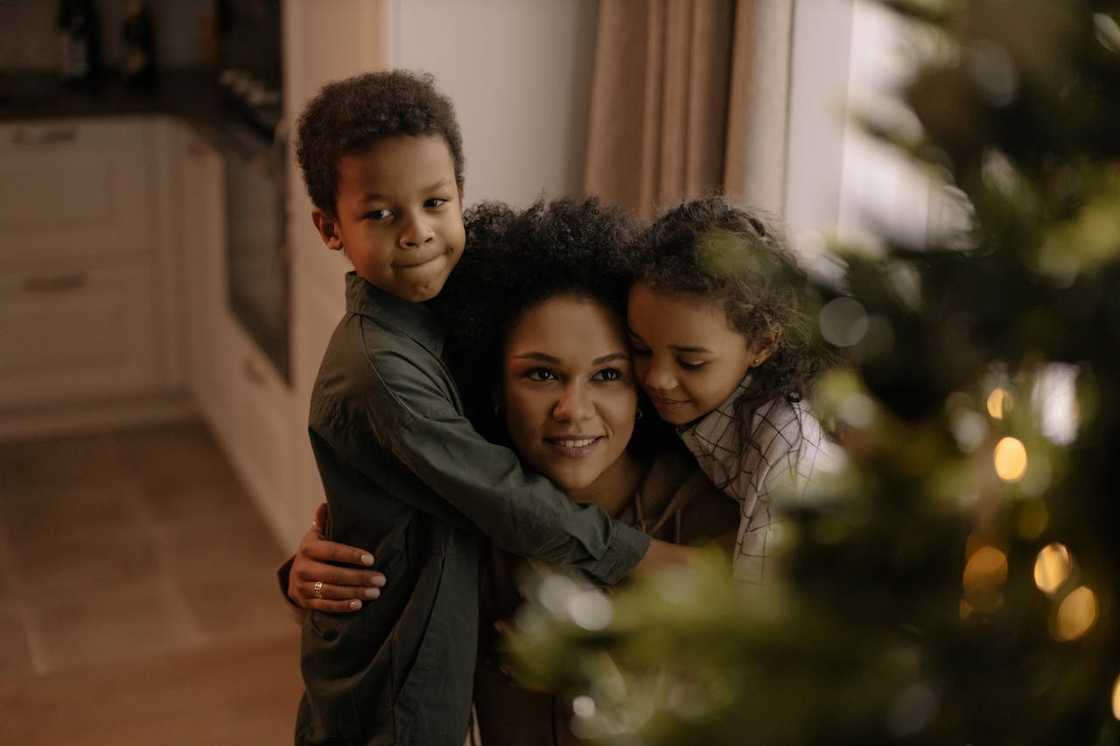 A woman hugs her children at home.