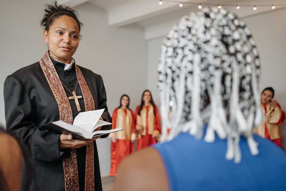 A female pastor reads from a book while speaking to a small group. A female pastor reads from a book while speaking to a small group.