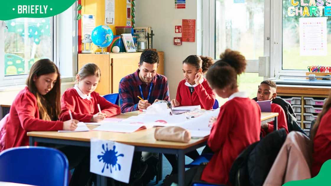 A teacher and students sat together at a table. A teacher and students sat together at a table.