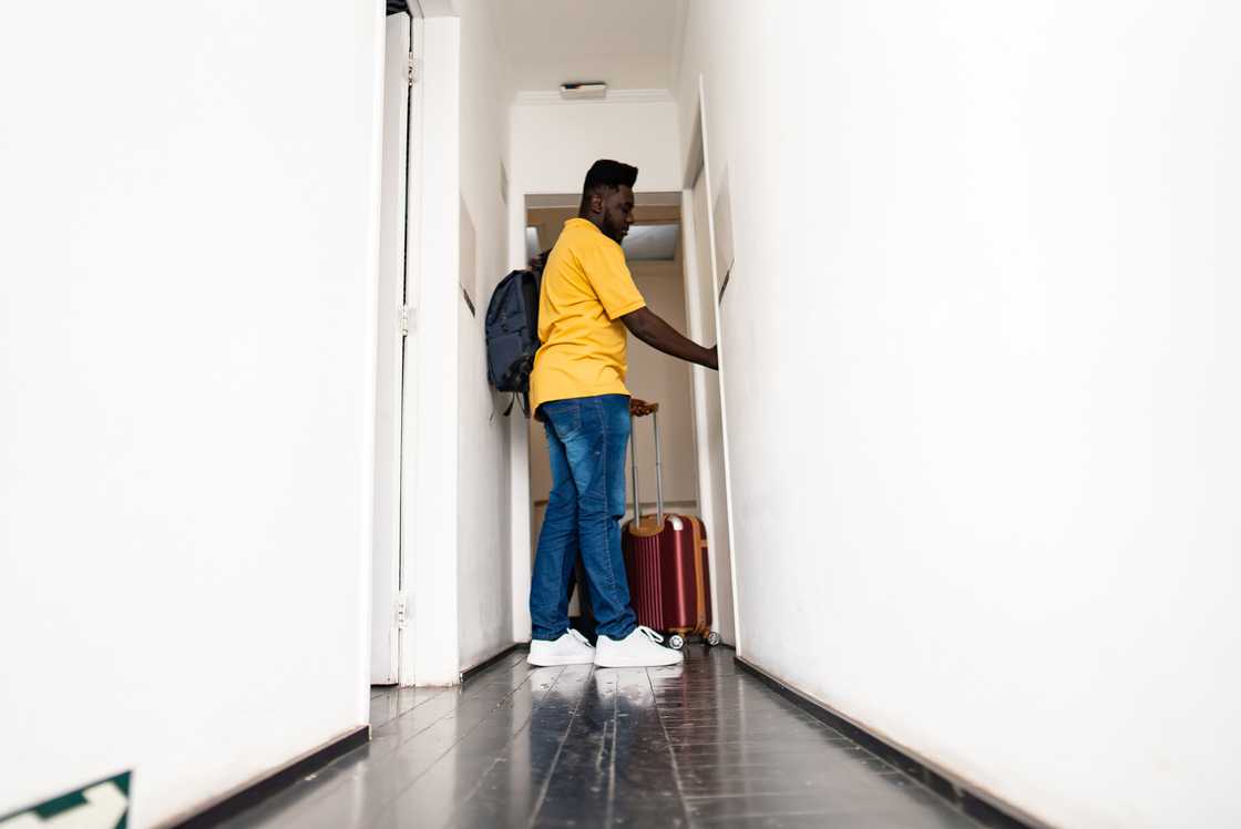 A mid-adult man is opening the hotel room door
