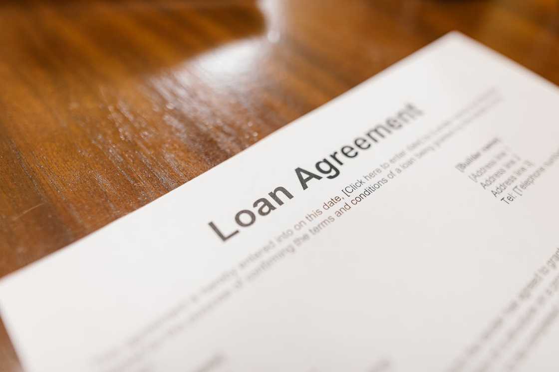 A loan agreement document lies on a wooden table.