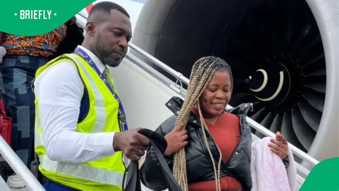 A passenger carrying her personal belongings walked up the boarding stairs next to a large jet engine turbine