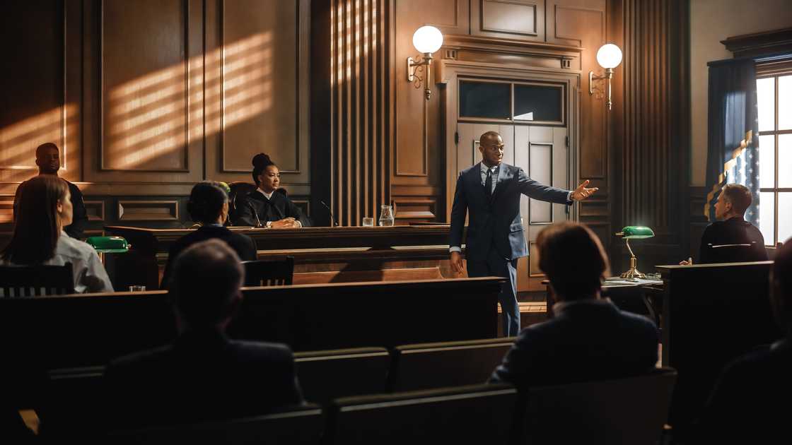 Courtroom scene with a lawyer in a blue suit addressing the judge.