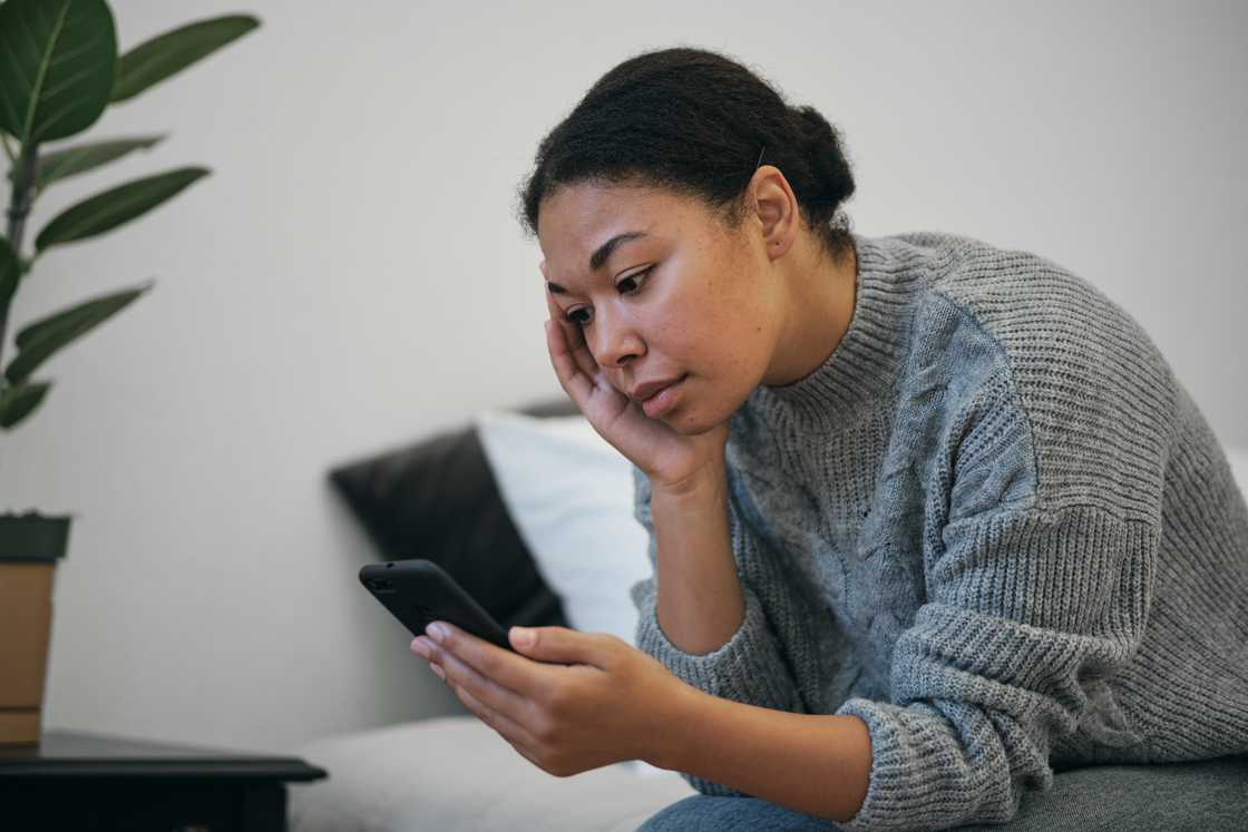 A sad woman scrolls on her phone