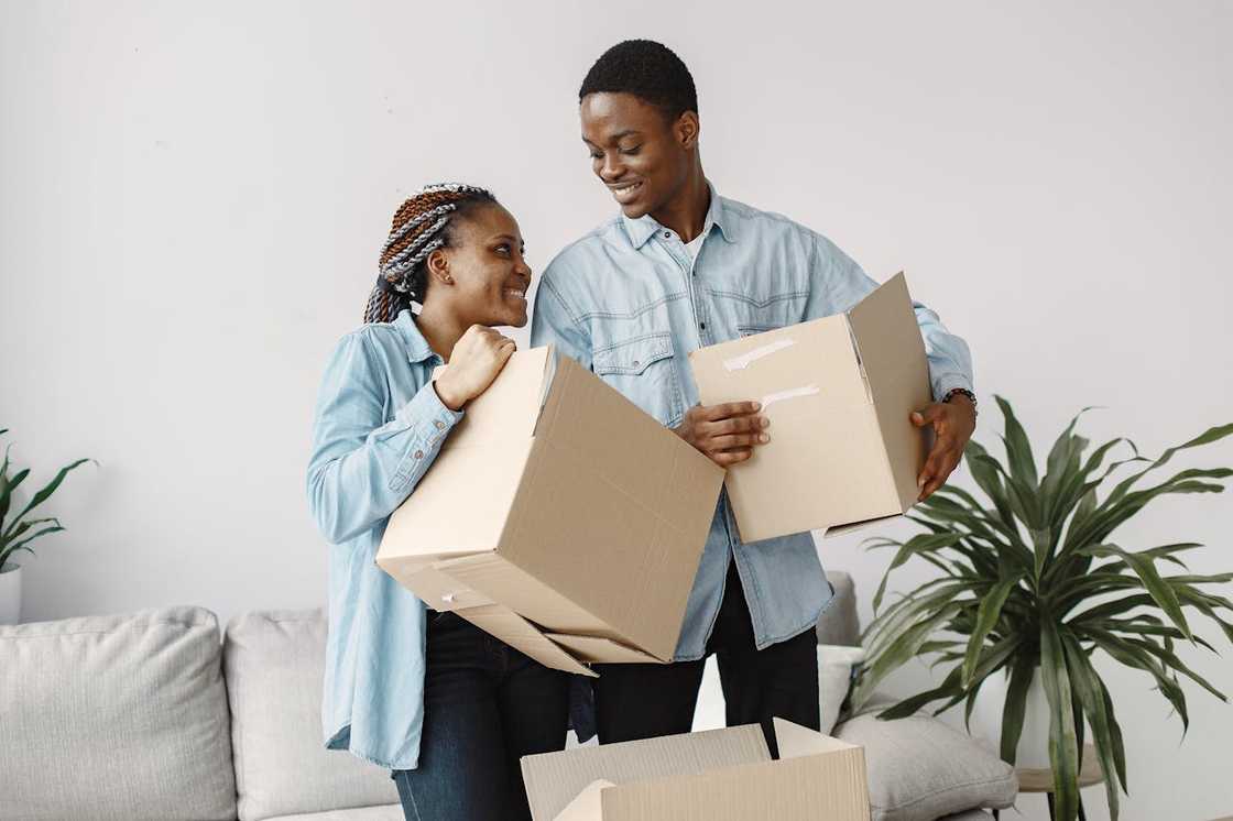 A smiling couple holding cardboard boxes while moving into a new home. A smiling couple holding cardboard boxes while moving into a new home.