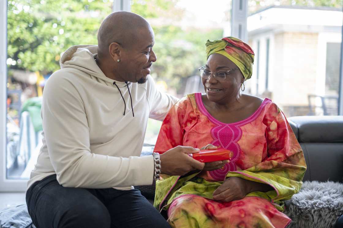 Man giving boxed gift to woman in living room.