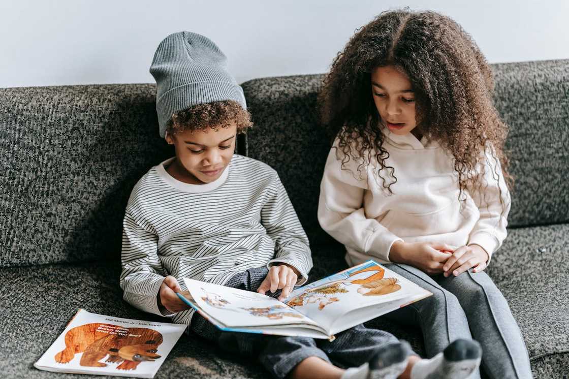 Two children read an interesting book during a family gathering.