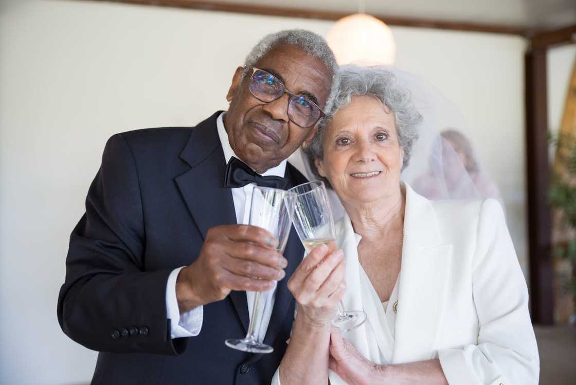 Elderly couple in formal attire raising champagne glasses in celebration.