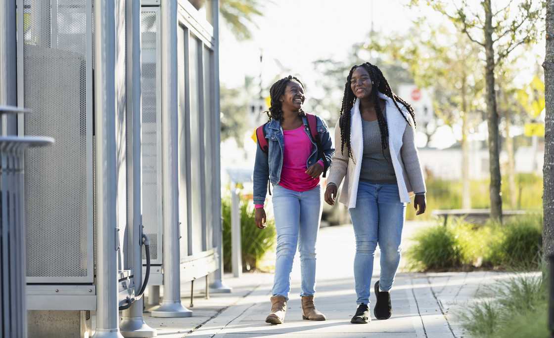 Two sisters walking together as they converse Two sisters walking together as they converse