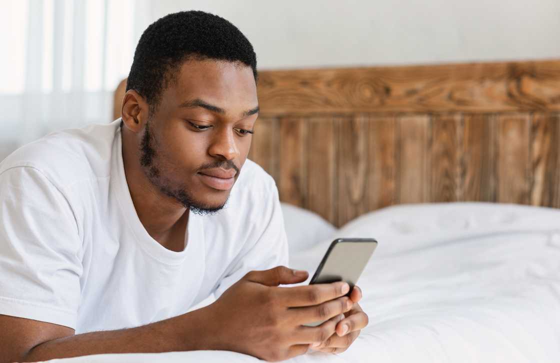 A man using mobile phone while lying in bed