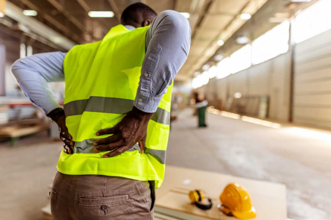 A man with back pains at a construction job A man with back pains at a construction job