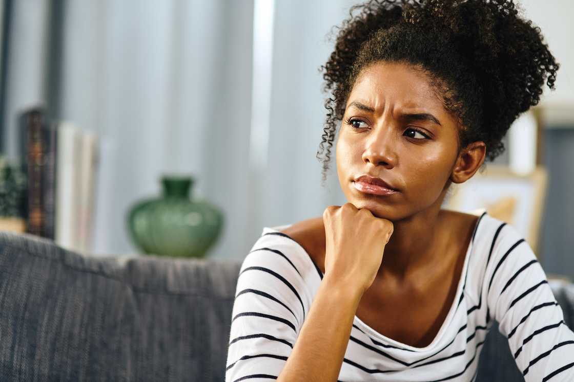 A young woman looking thoughtful while relaxing at home
