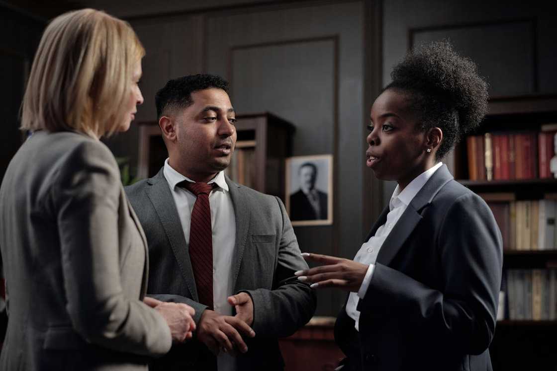 Three people in suits having a serious discussion in an office.
