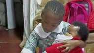 Pic of little girl doing homework while holding sibling gains varied replies as peeps discuss firstborns